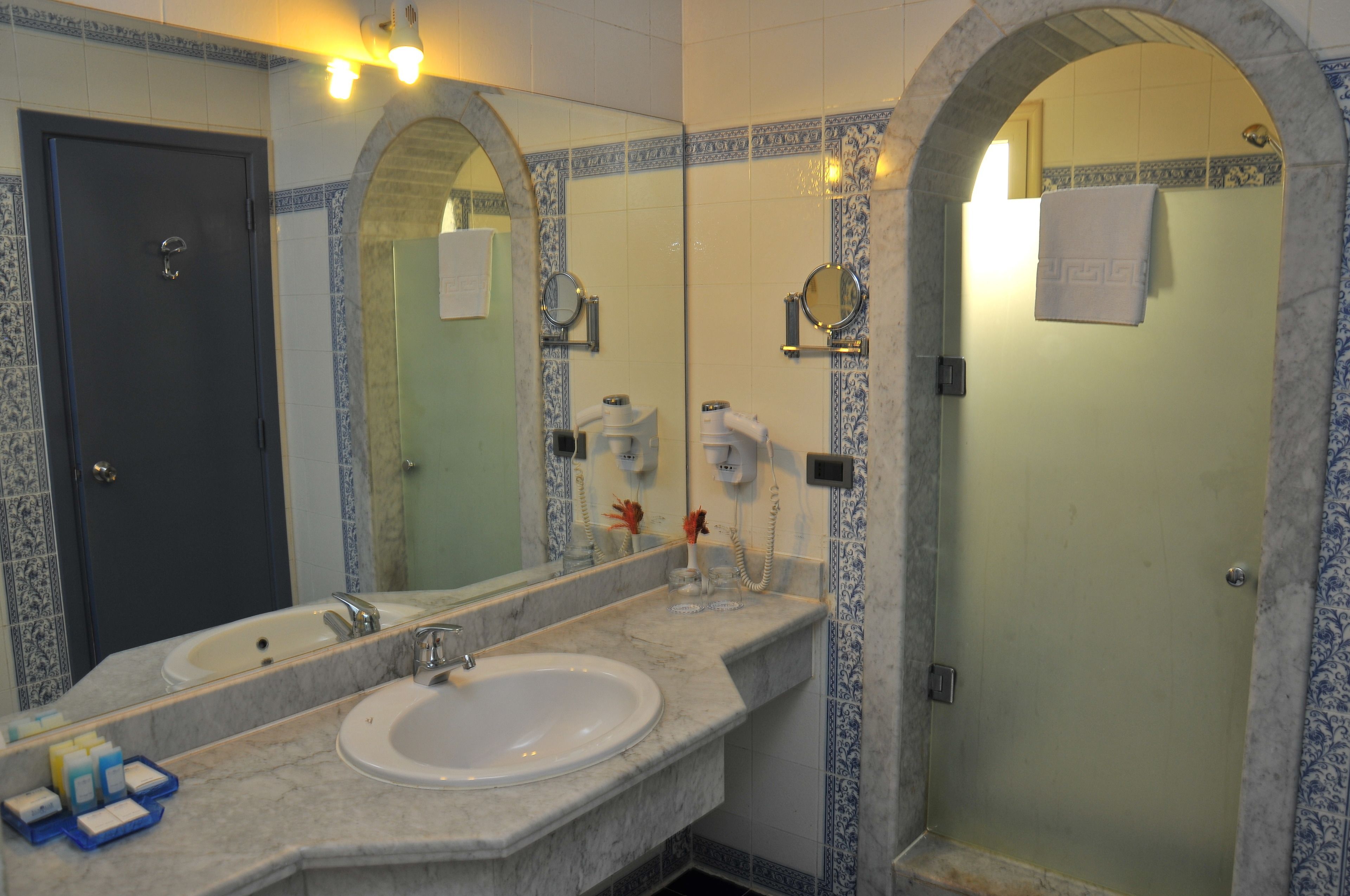A bathroom with a large mirror, two sinks, and a shower area.