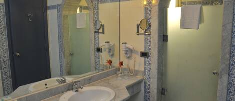 A bathroom with a large mirror, two sinks, and a shower area.