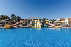 A swimming pool with multiple slides and a covered area.