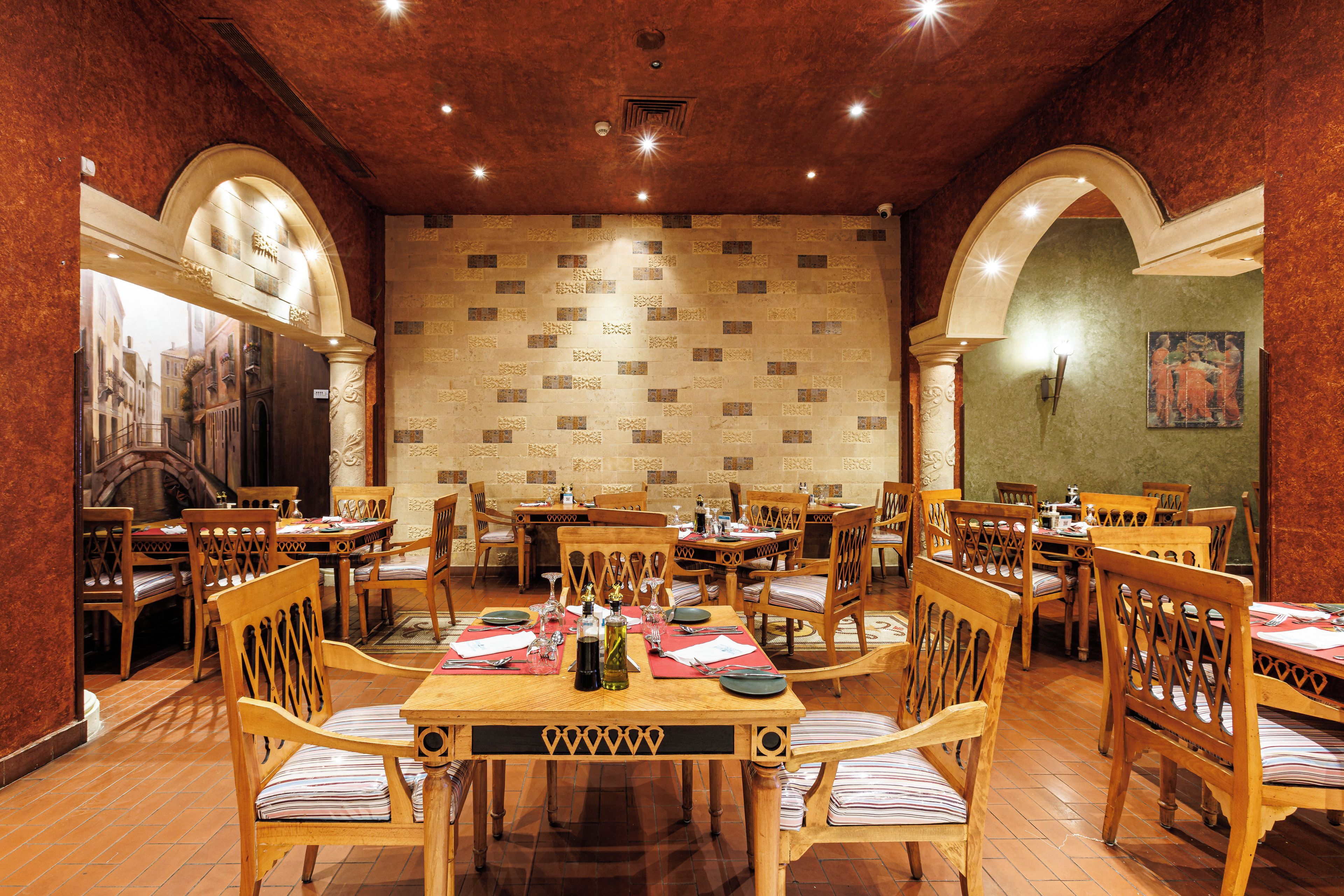 Un restaurante con varias mesas y sillas, un muro con diseño y un cuadro en la pared.