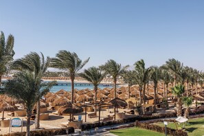 A beach resort with thatched umbrellas, palm trees, and lounge chairs. - SUNRISE Royal Makadi Resort - All inclusive (Makadi Bay)