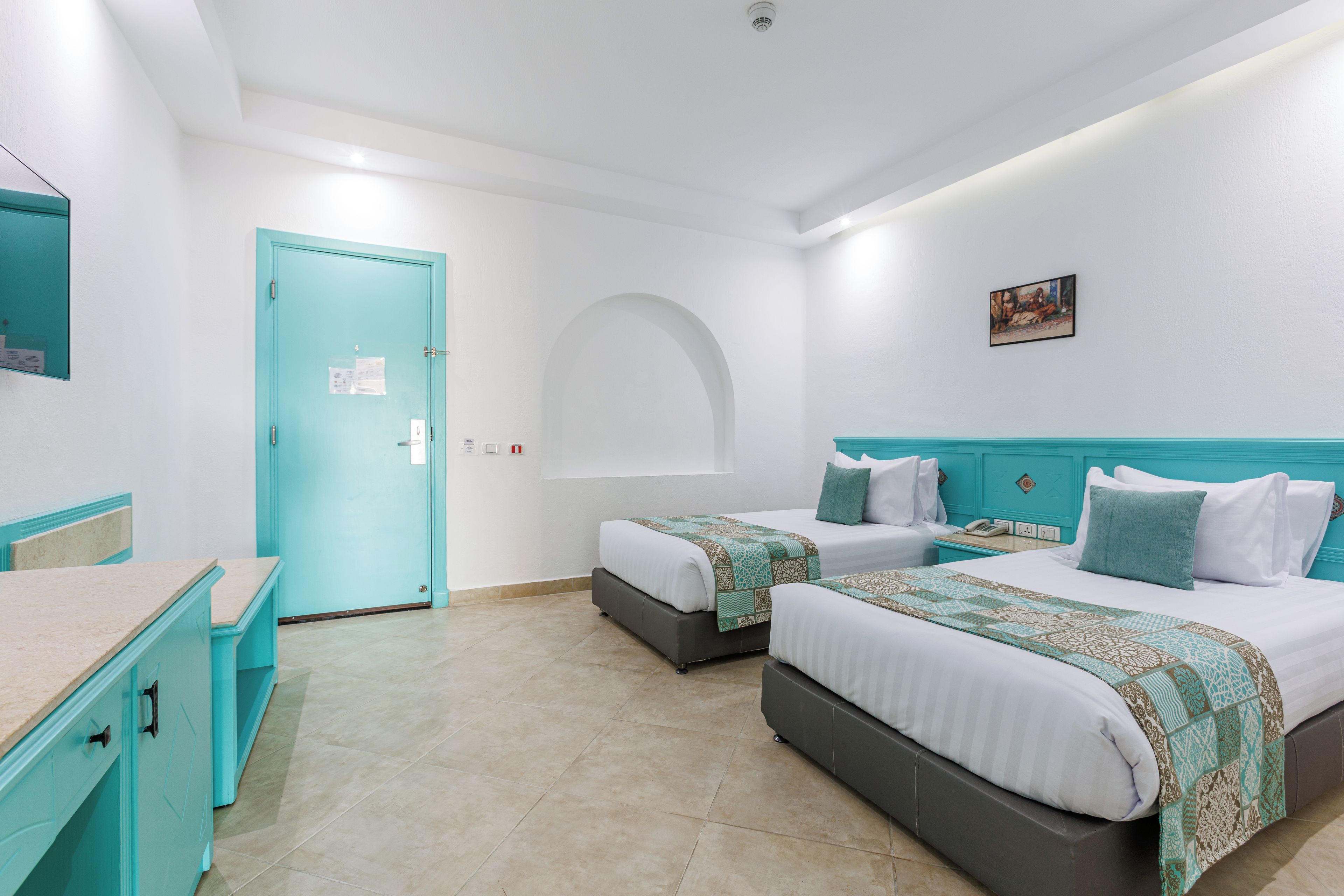 Habitación de hotel con dos camas, un escritorio y la puerta del baño.