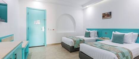 Habitación de hotel con dos camas, un escritorio y la puerta del baño.