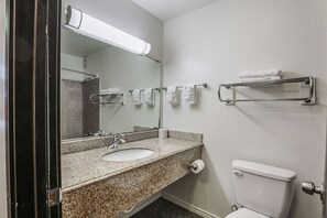 A bathroom with a granite countertop sink, a mirror, a towel rack, and a toilet. - Motel 6 Pasadena, TX (Pasadena)