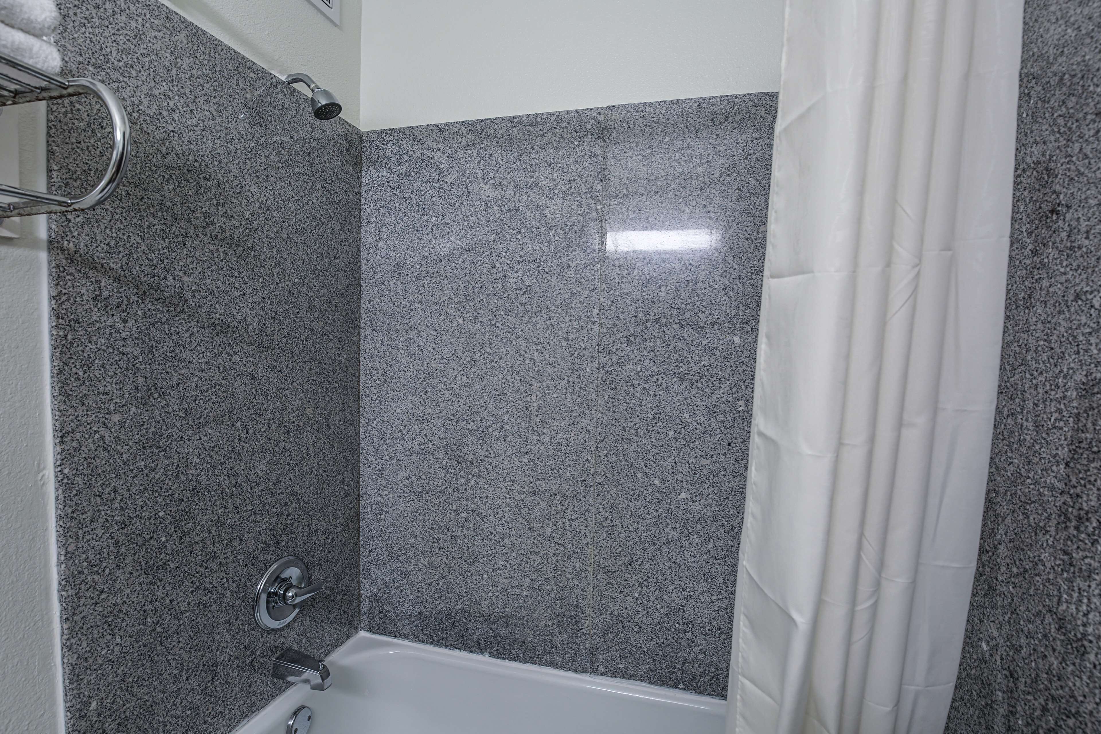 A bathroom with a shower, a bathtub, and a towel rack.