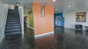A modern interior with a staircase, a reception area, and a wall-mounted welcome sign. - Motel 6 Pasadena, TX (Pasadena)