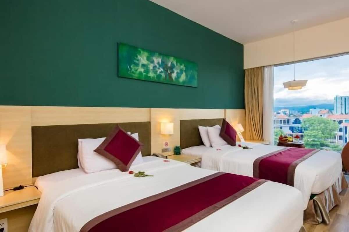 A hotel room with two beds, a large window with a city view, and a green wall with a painting.