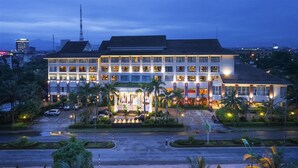 A multi-story hotel with a well-lit entrance, a parking area, and a landscaped garden with palm trees. - Sai Gon Quang Binh Hotel (Dong Hoi)