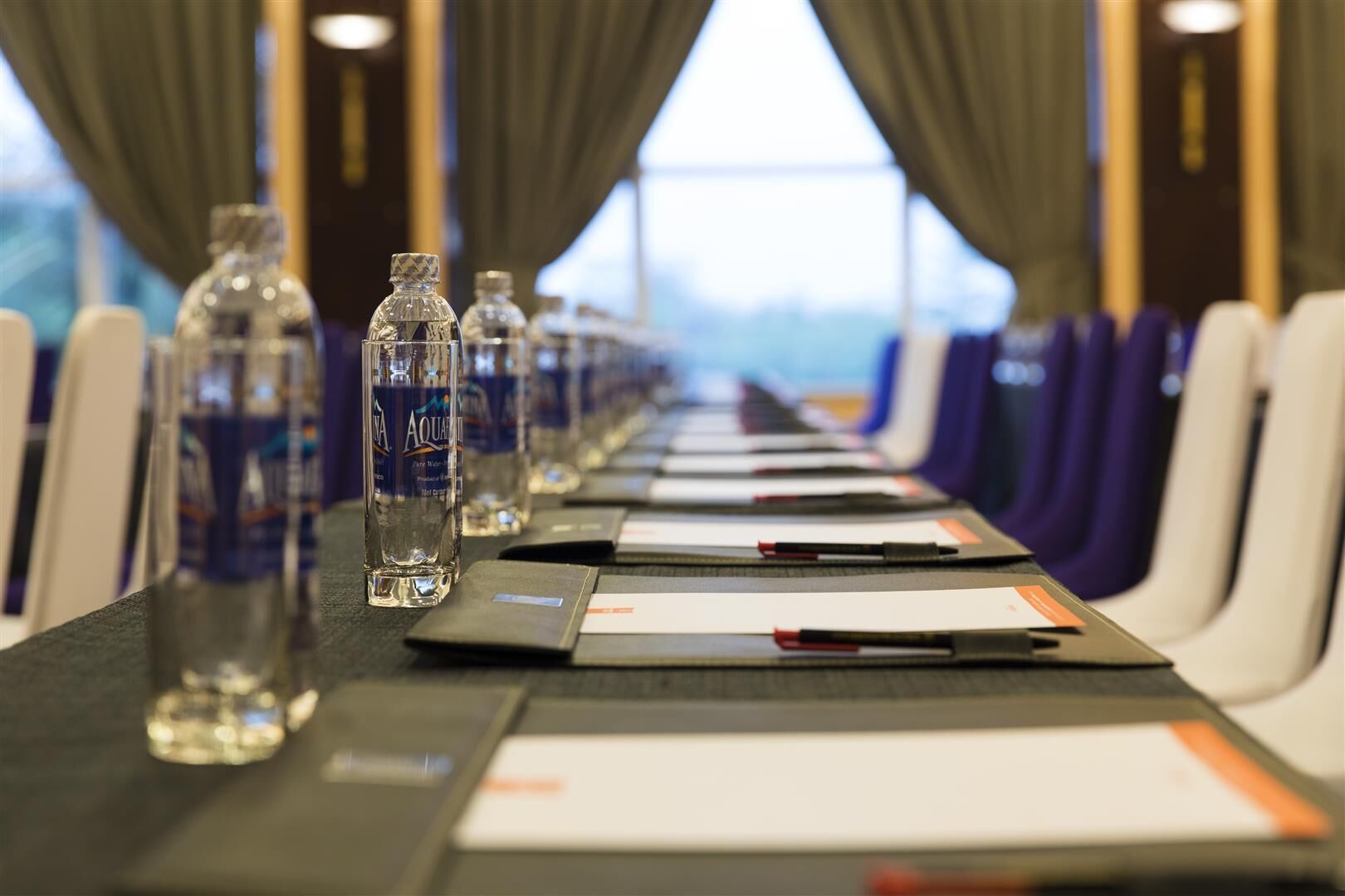 A conference room with a long table, water bottles, and name cards.