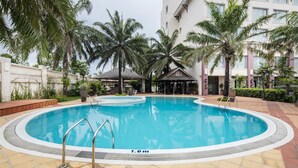 A swimming pool with a 1.6m depth marker, surrounded by palm trees and a building with a white facade. - Sai Gon Quang Binh Hotel (Dong Hoi)