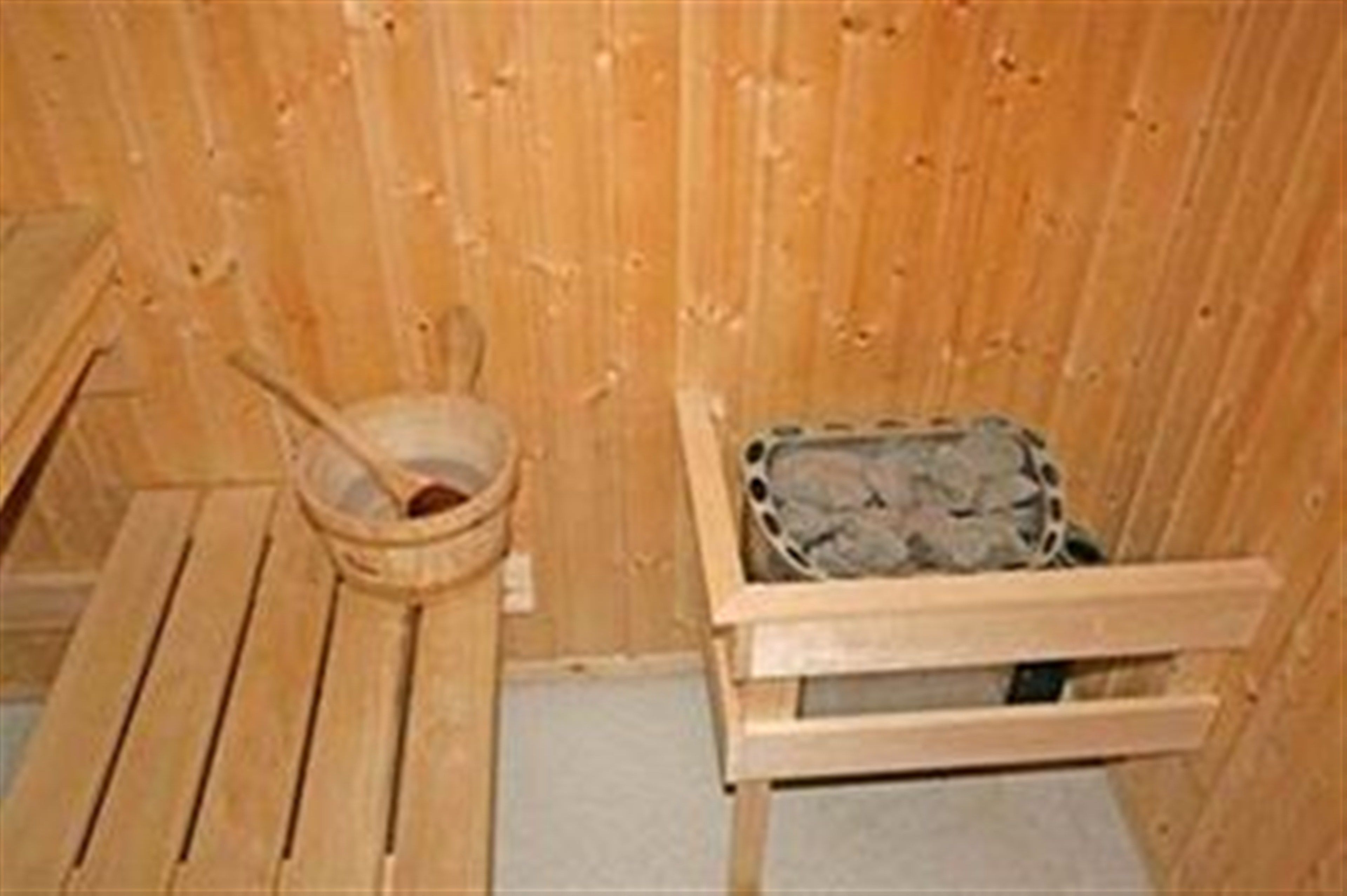 Ein Holz-Saunaraum mit einer Bank, einem Eimer und einem mit Steinen gefüllten Behälter.
