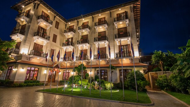 Un hotel gran de diverses plantes amb un pati central, múltiples balcons i una façana ben il·luminada.