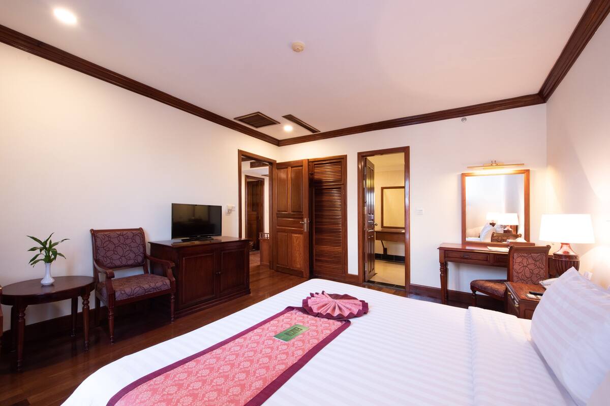 A hotel room with a bed, a desk, a chair, a television, and a mirror.