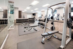Un gimnasio con equipo de levantamiento de pesas, cintas de correr y un espejo grande.