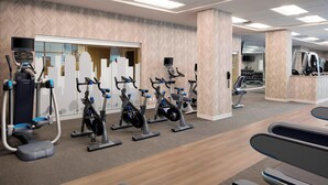 A gym with various exercise machines, a mirrored wall, and a herringbone-patterned wall. - SpringHill Suites by Marriott Indianapolis Downtown (Indianapolis)