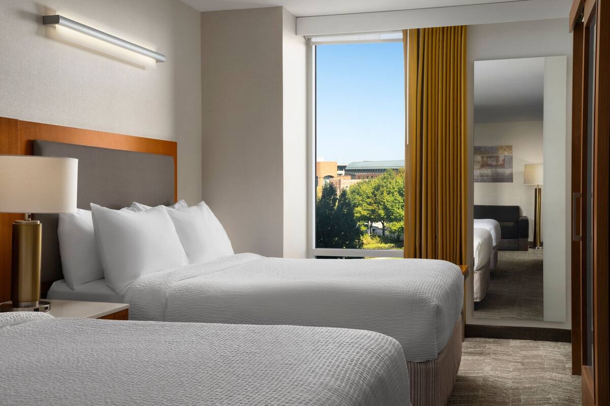 Une chambre d’hôtel avec deux lits, une grande fenêtre et une vue sur l’extérieur.