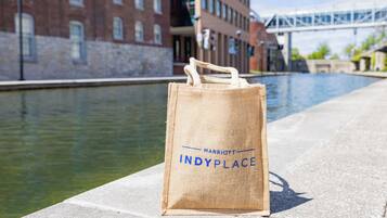 A burlap bag with "Marriott IndyPlace" text on a concrete surface near a canal with buildings in the background.