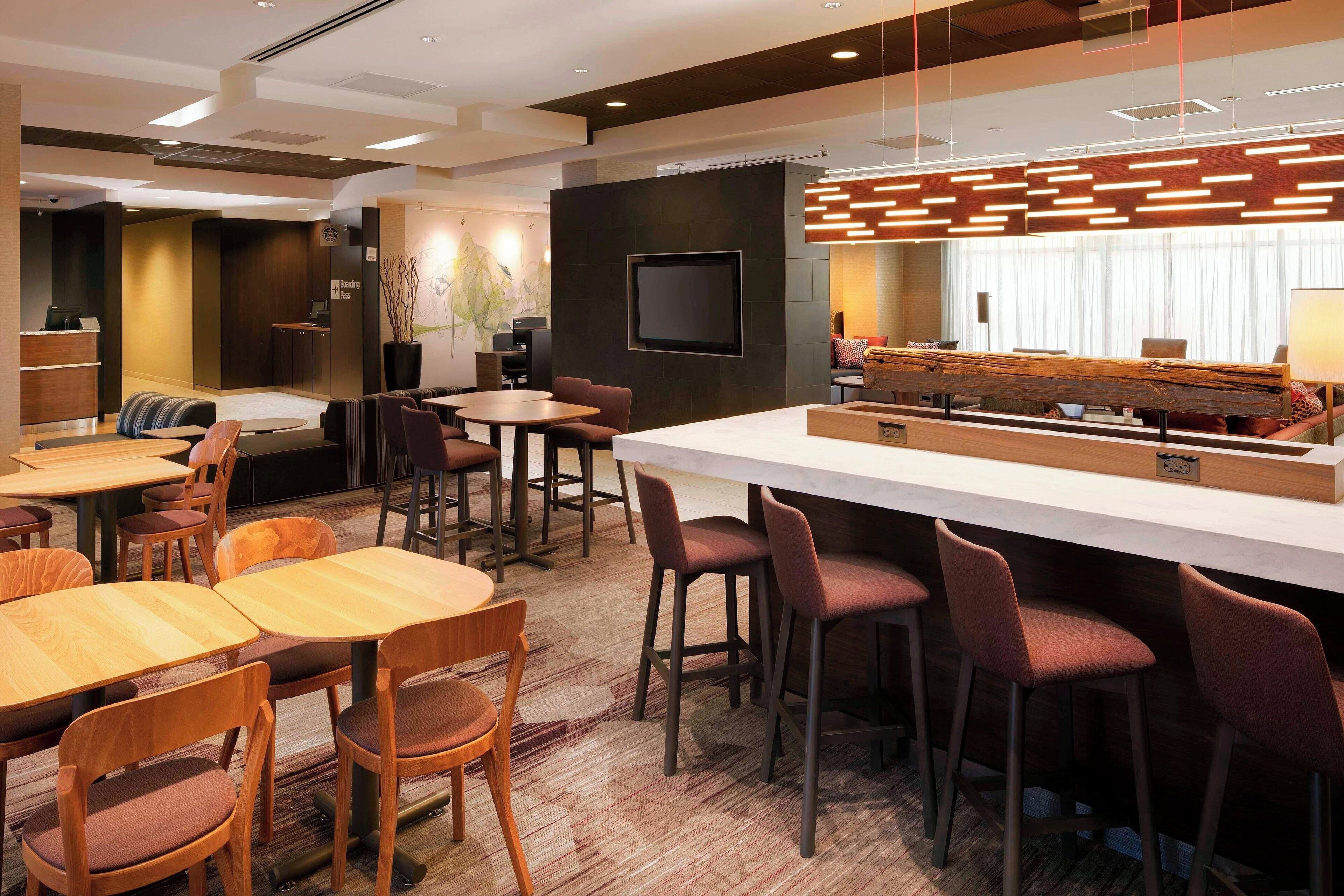 Un moderno vestíbulo de hotel con recepción, zona de estar y bar.