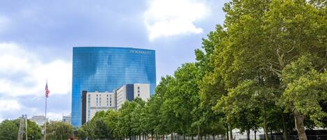 Un hôtel JW Marriott doté d’une façade moderne en verre, entouré d’un parc bien entretenu avec des arbres et une pelouse.