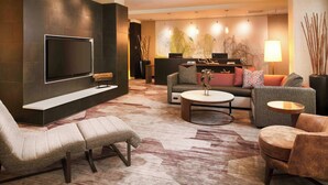 Ein modernes Wohnzimmer mit Flachbildfernseher, bequemen Sitzmöglichkeiten, einem Couchtisch und einer Wanddekoration.