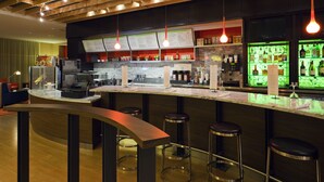 Eine moderne Bar mit gebogener Theke, Barhocker und hängenden Pendelleuchten.
