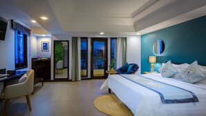 Quarto de hotel moderno com uma cama grande, uma escrivaninha e vista para o exterior.
