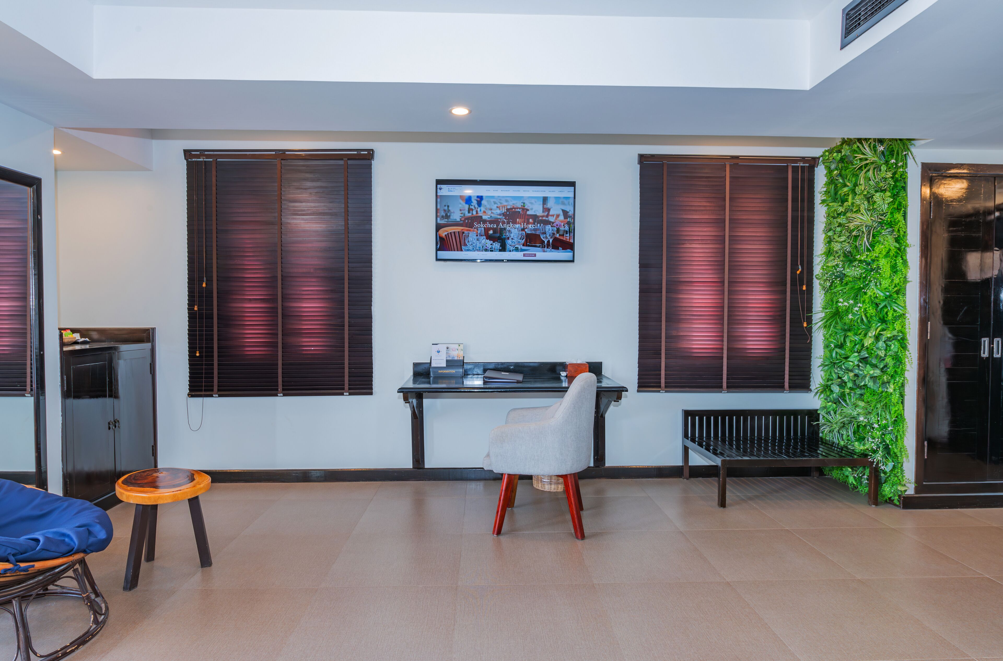 Una sala de estar moderna con una mesa de vidrio, una silla gris, un banco de madera y un televisor montado en la pared.