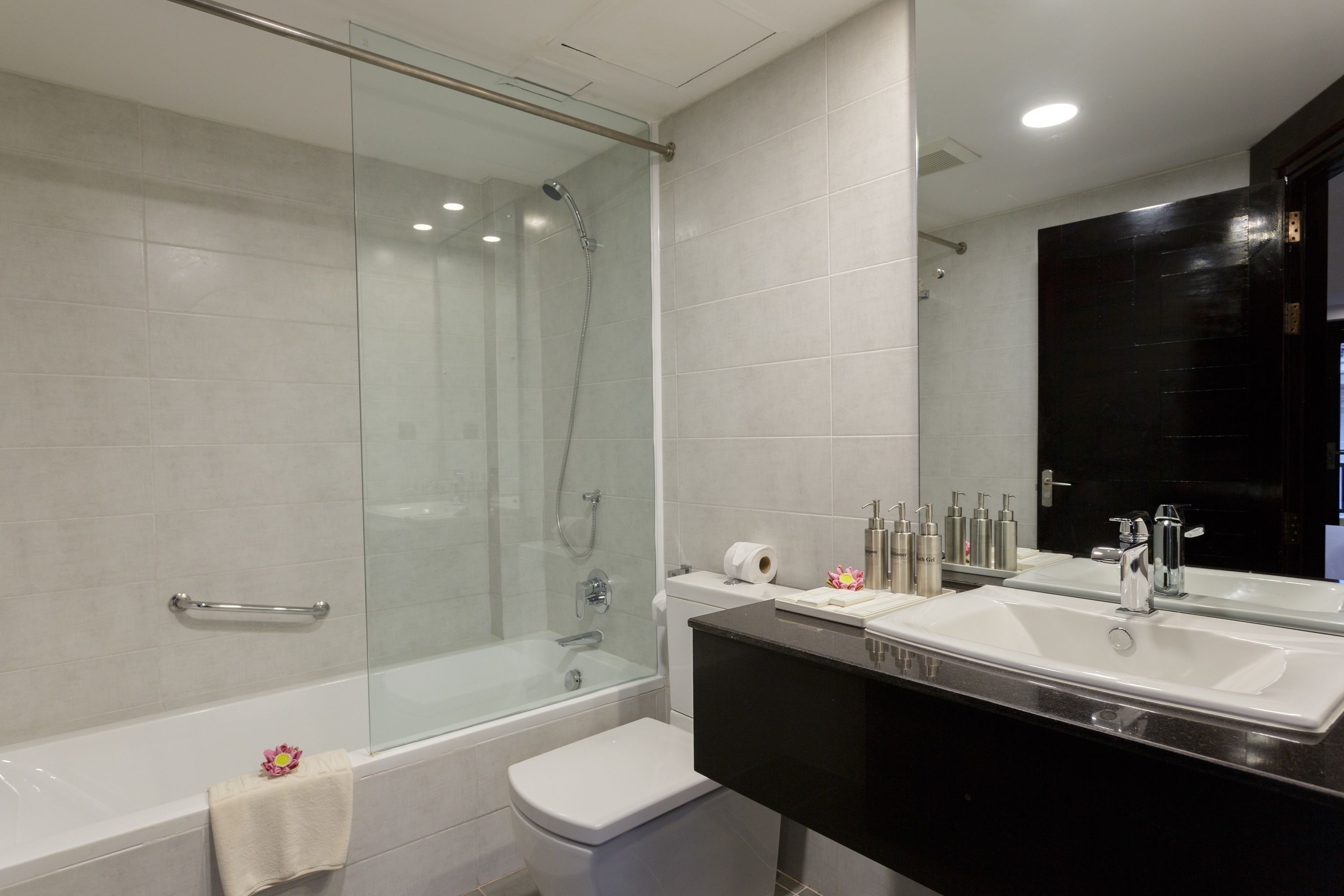 A modern bathroom with a glass-enclosed shower, a white toilet, and a vanity with two sinks.
