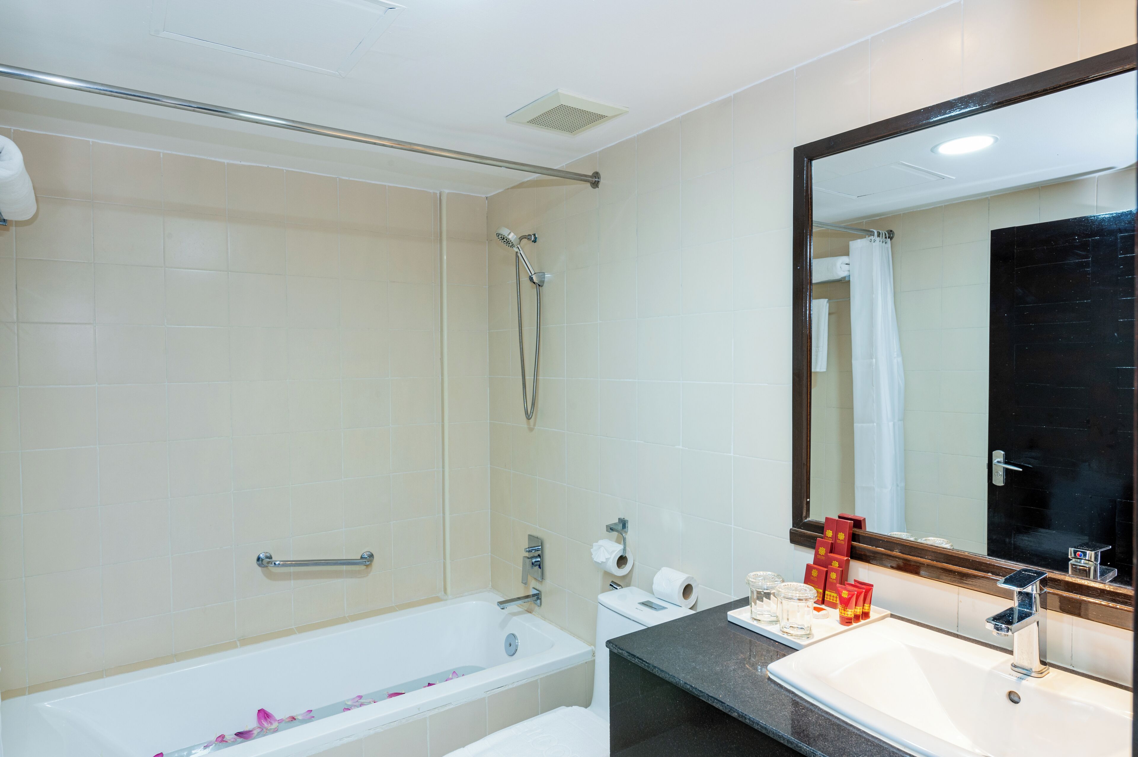 A bathroom with a bathtub, a sink, a large mirror, and a shower.