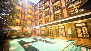 Um hotel com piscina, várias varandas e áreas de estar ao ar livre.
