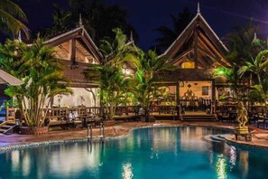 A pool area with two wooden structures, palm trees, and a statue. - Angkoriana (Siem Reap)