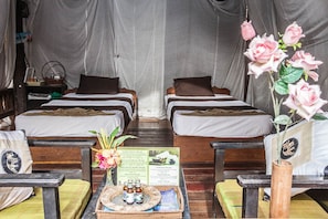 A room with two beds, a small table with bottles and a menu, and a vase with flowers. - Angkoriana (Siem Reap)