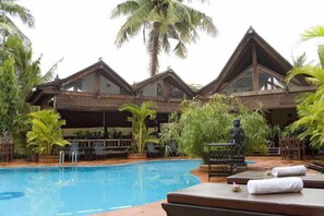 A pool area with a clear view of a building with a triangular roof and a statue in the foreground. - Angkoriana (Siem Reap)
