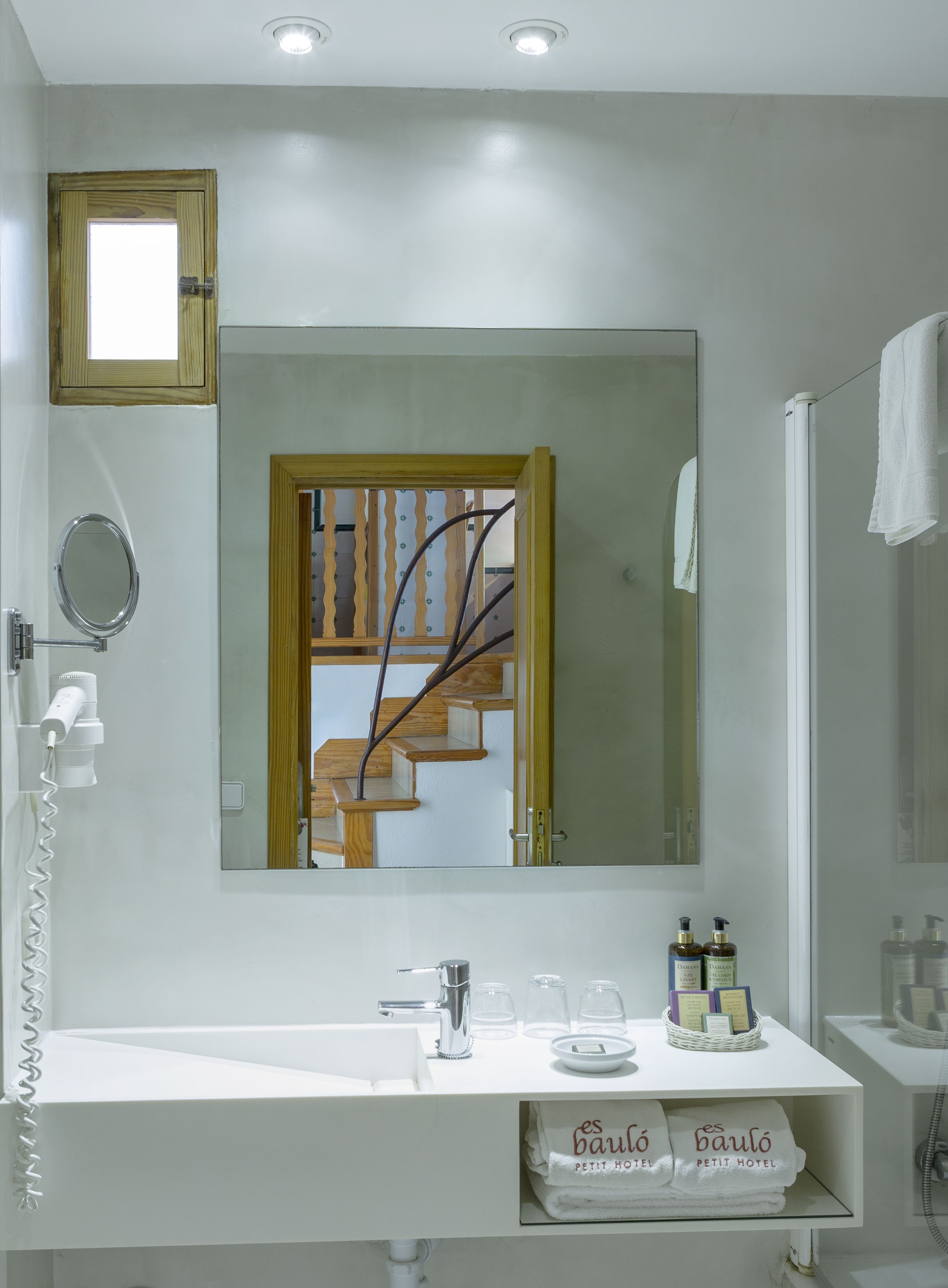 A bathroom with a large mirror, a sink, a towel rack, and a shower area.