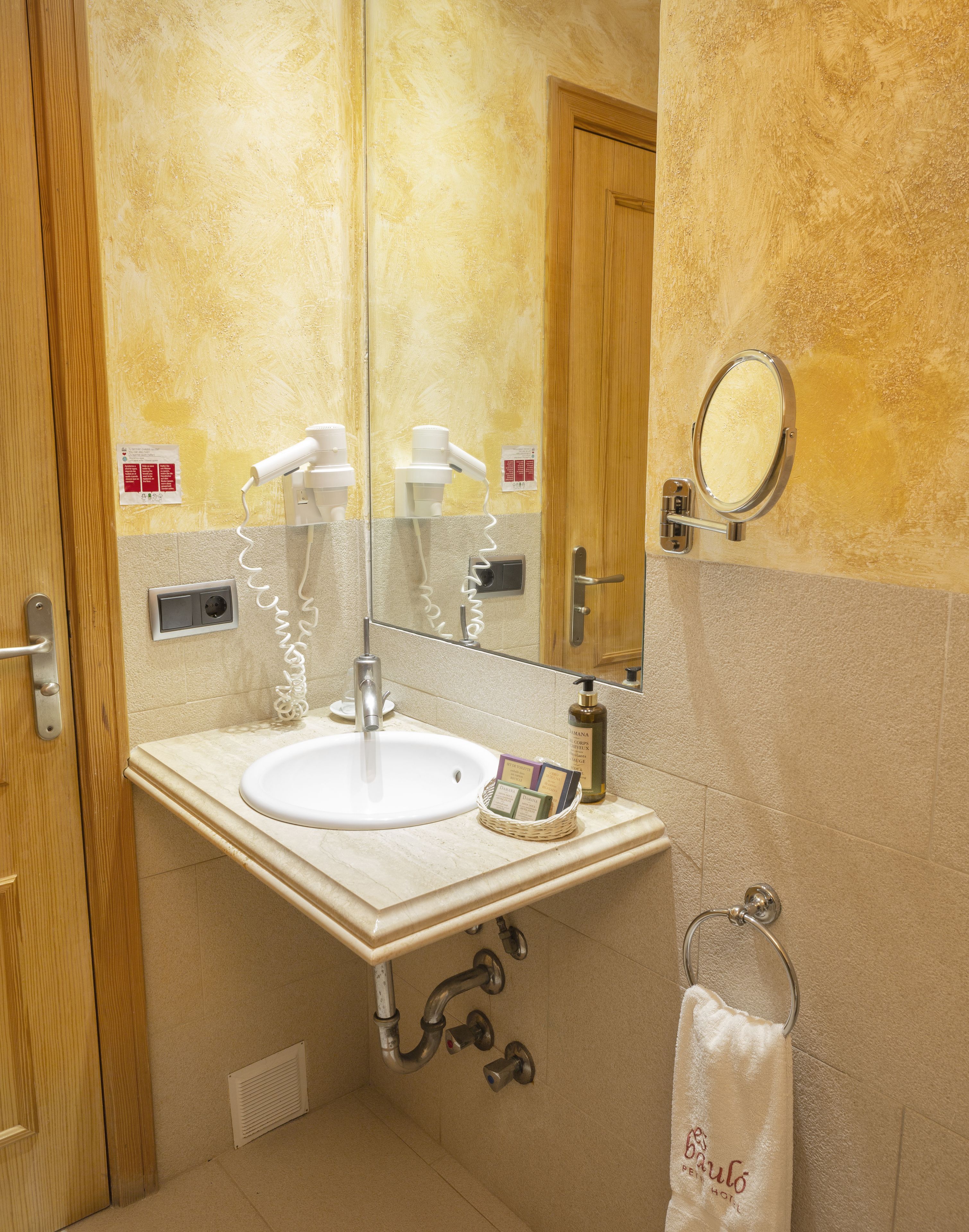Une salle de bain équipée d’un lavabo, d’un miroir, d’un sèche-cheveux et d’un porte-serviettes.