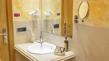 Une salle de bain équipée d’un lavabo, d’un miroir, d’un sèche-cheveux et d’un porte-serviettes.