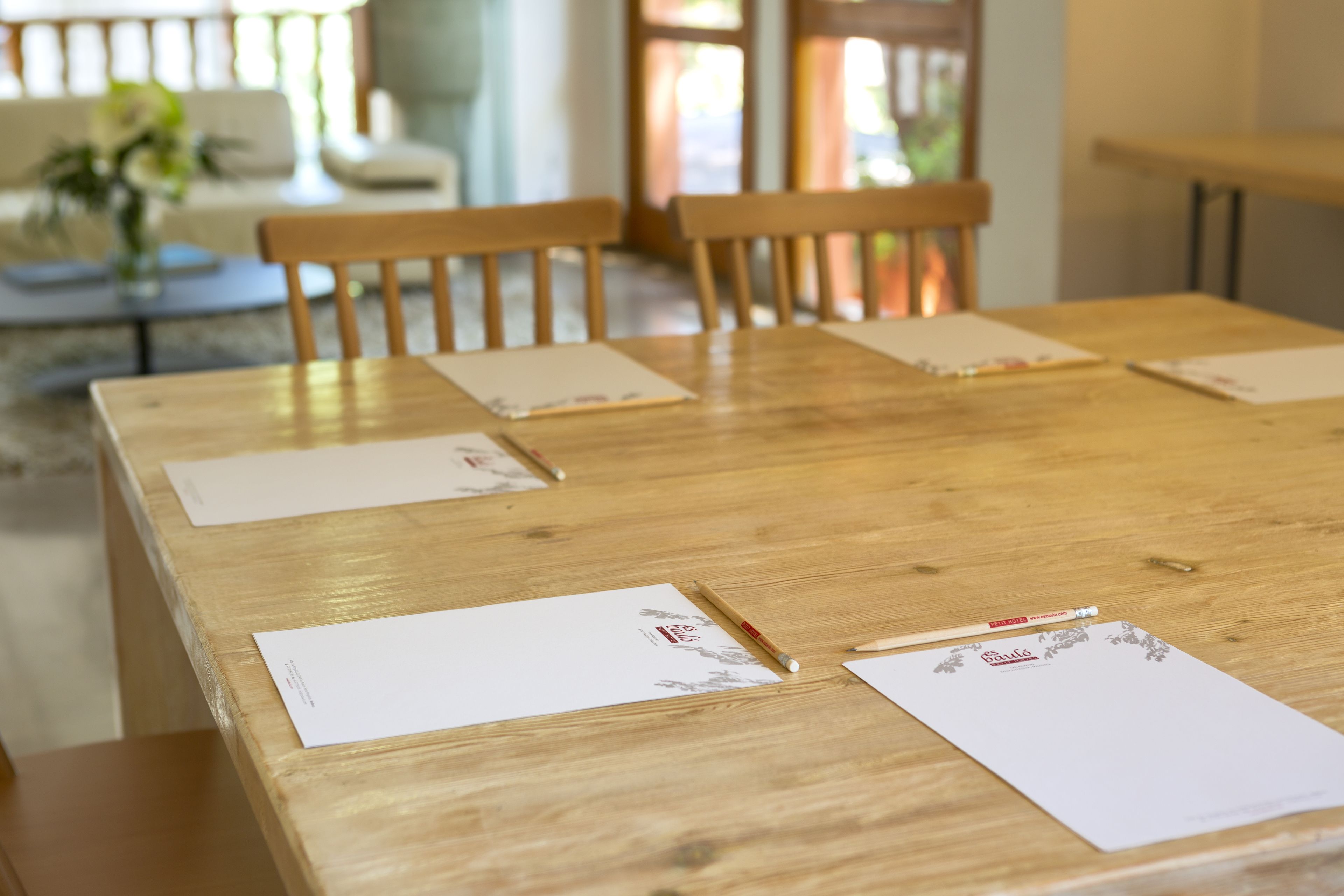 Una mesa de madera con cuatro sillas, papeles y un bolígrafo.
