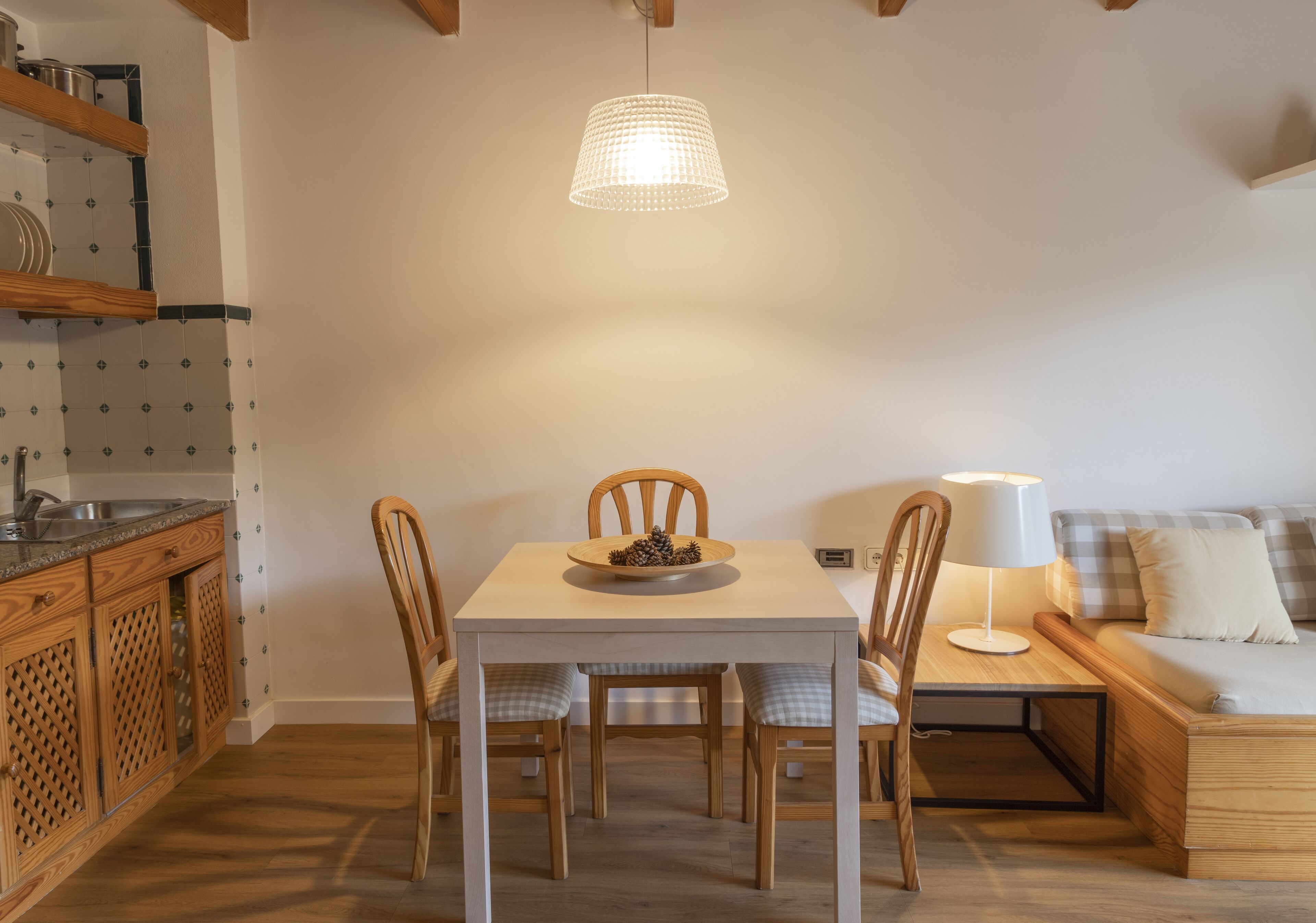 Ein Essbereich mit Tisch, Stühlen, einer Pendelleuchte, einer Couch und einer Lampe.
