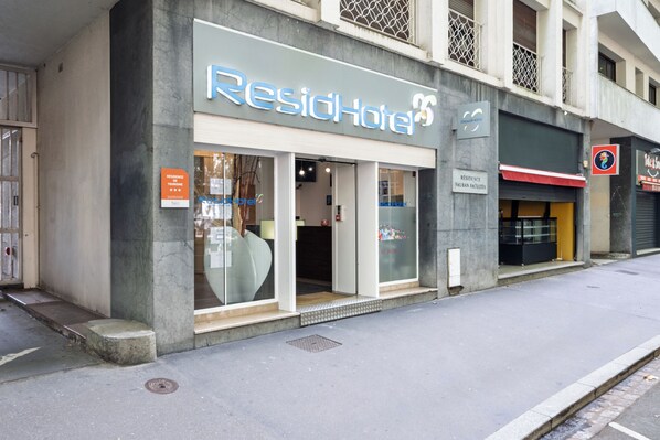 Un hotel llamado 'ResidHotel' con una fachada moderna, grandes ventanales y una entrada visible.