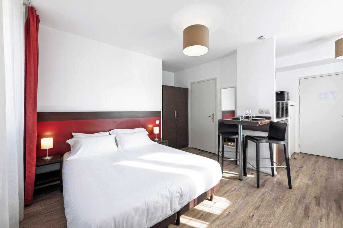 A hotel room with a bed, a desk, and a chair.