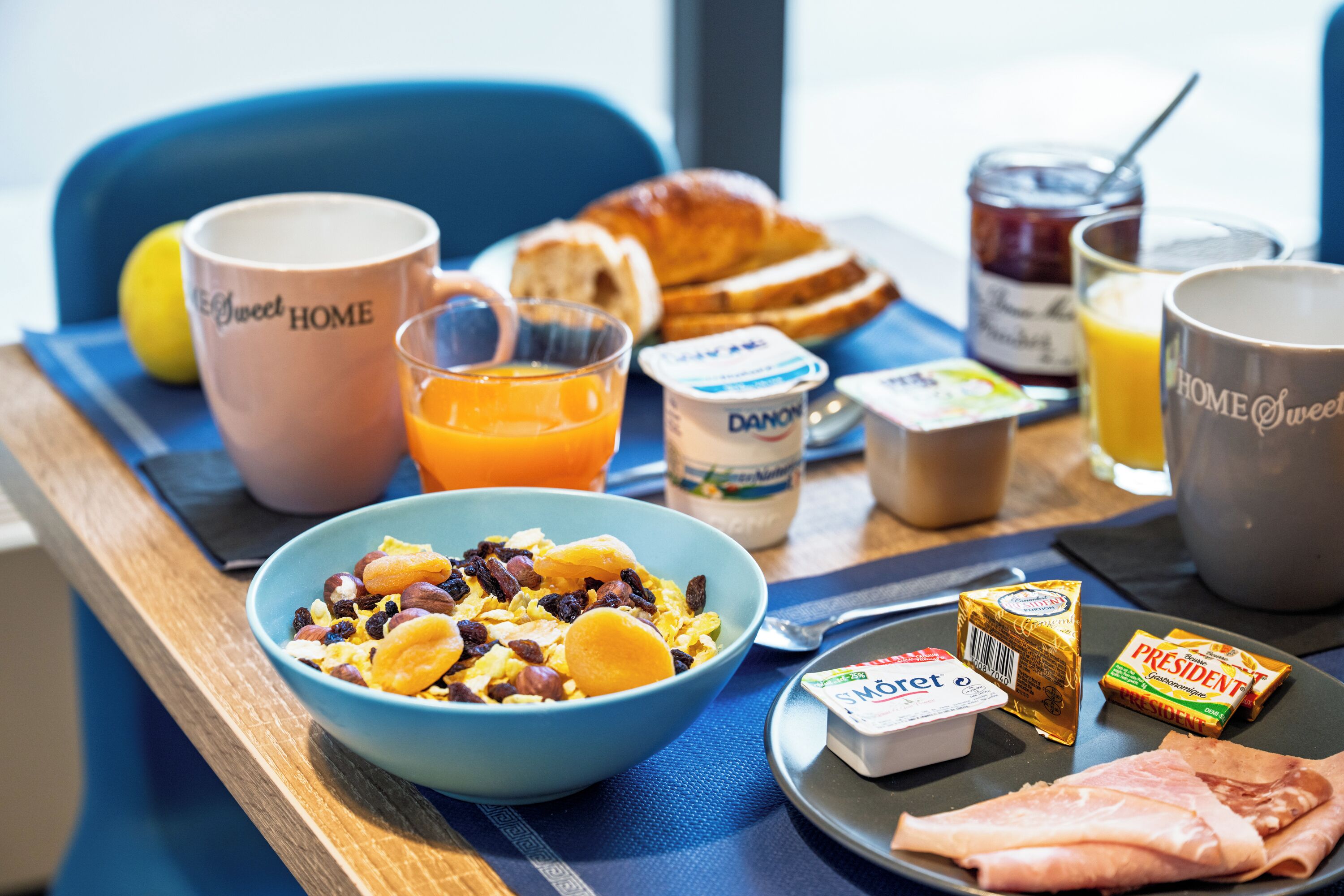Een ontbijfwagen met een croissant, sinaasappelsap, yoghurt en een kom ontbijtgranen.