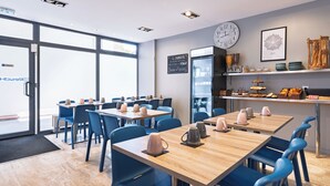 A modern cafe with wooden tables and blue chairs, a large clock, and a chalkboard menu on the wall. - Residhotel Lille Vauban (Lille)