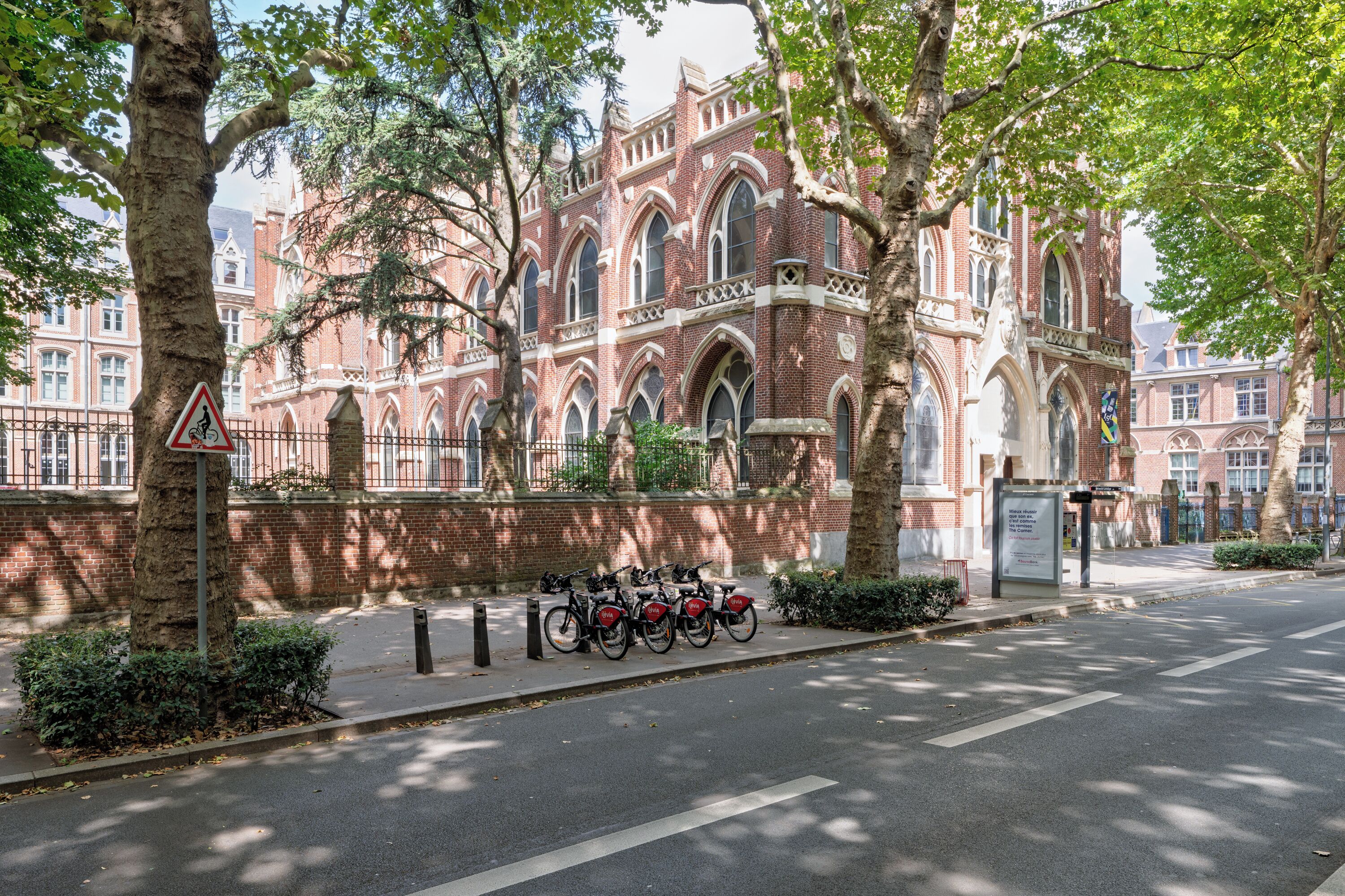 A historic building with red brick architecture, a bicycle parking area, and a pedestrian pathway.