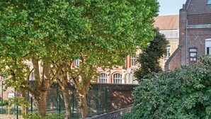 A brick building with a red-tiled roof, surrounded by trees and a brick wall. - Residhotel Lille Vauban (Lille)