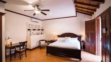 A hotel room with a bed, desk, chair, and a ceiling fan.