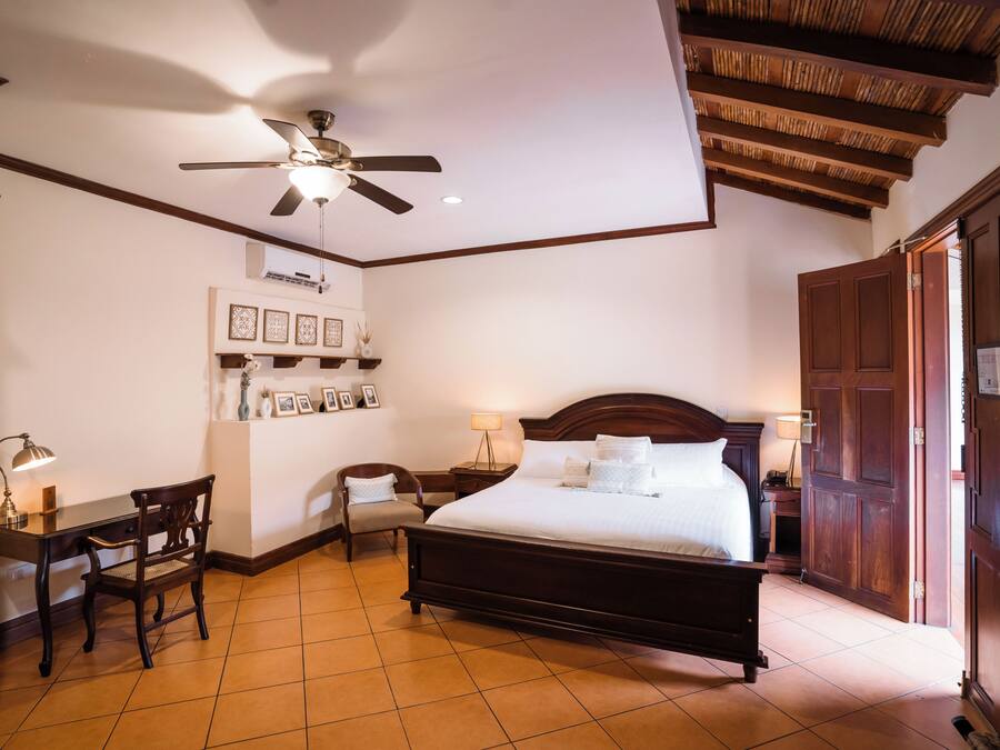 A hotel room with a bed, desk, chair, and a ceiling fan.