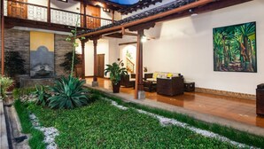 A traditional building with a covered patio, a stone sculpture, and a painting of a forest. - Hotel Plaza Colon (Granada)