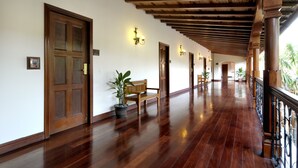 A hallway with wooden flooring, a bench, potted plants, and doors. - Hotel Plaza Colon (Granada)