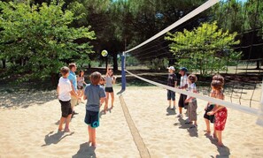 A group of people playing volleyball on a sandy court surrounded by trees. - Sowell LES Sentes (Carcans)