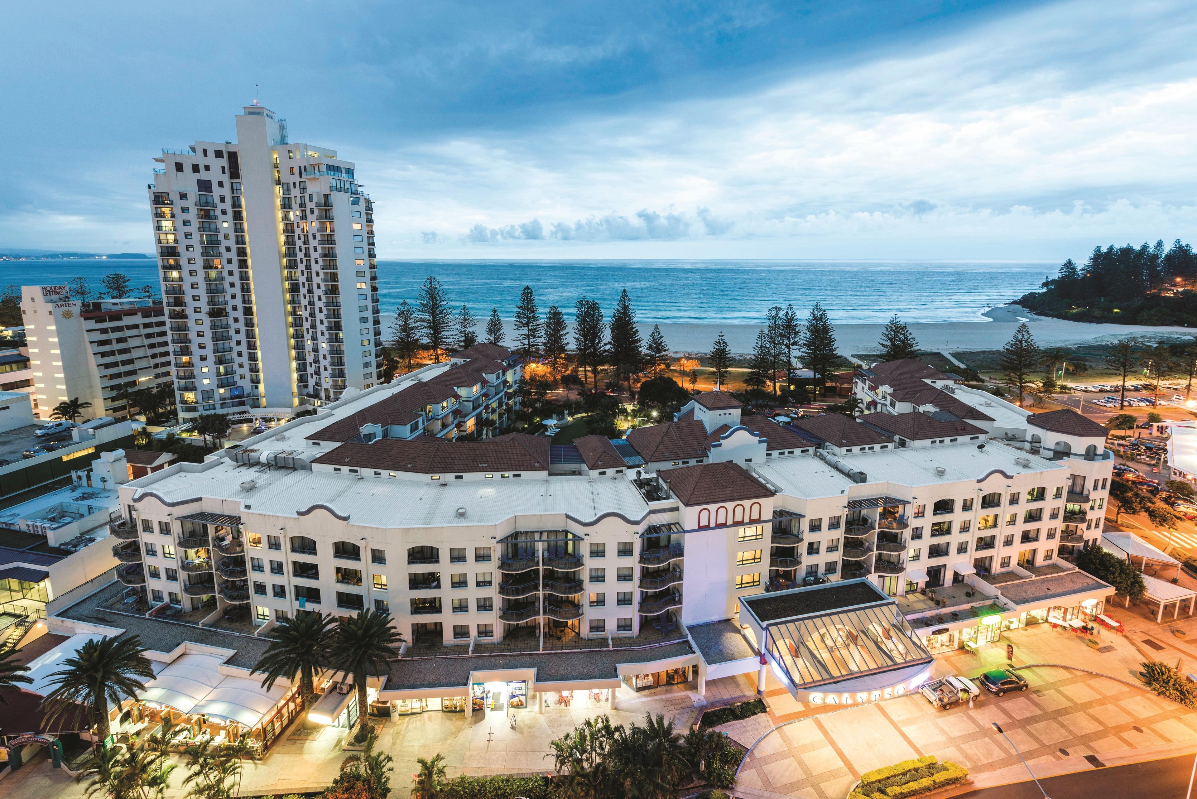 A hotel with multiple floors, a central courtyard, and a view of the ocean.